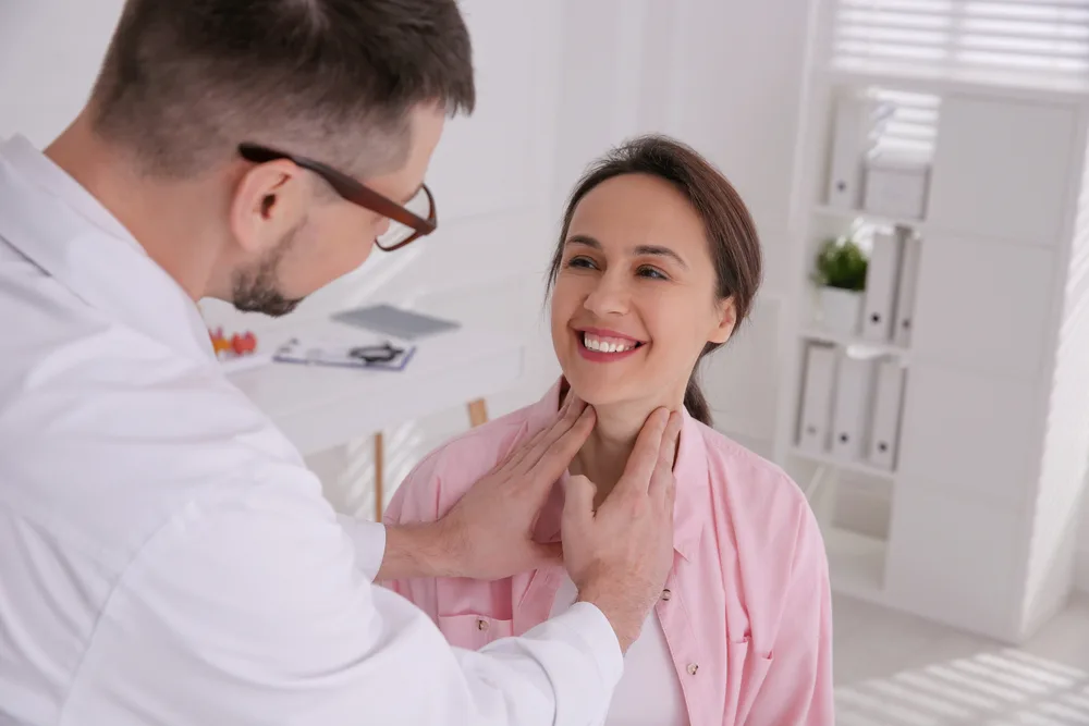 Thyroid surgeon examining a patient's neck during a consultation in a clinical office